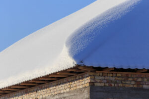 Snow on the roof of the house in winter .